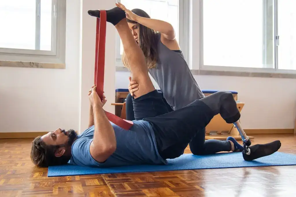 Man in rehabilitation exercises with a trainer, focusing on prosthetic leg recovery.