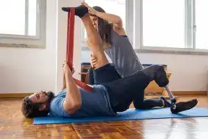 Man in rehabilitation exercises with a trainer, focusing on prosthetic leg recovery.